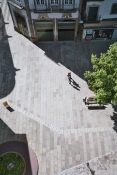 High angle view of a lone person walking on a sunlit urban square.