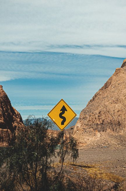 Curved road sign in the rugged landscape of San Salvador de Jujuy, Argentina.