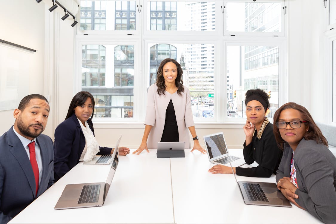 Free Woman Standing on the Center Table With Four People on the Side Stock Photo