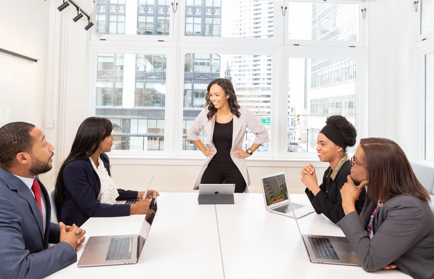 Diverse team engaged in a business meeting with laptops in a modern office setting.