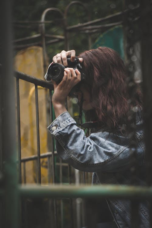 Woman in Denim Jacket Taking Photo with a Camera