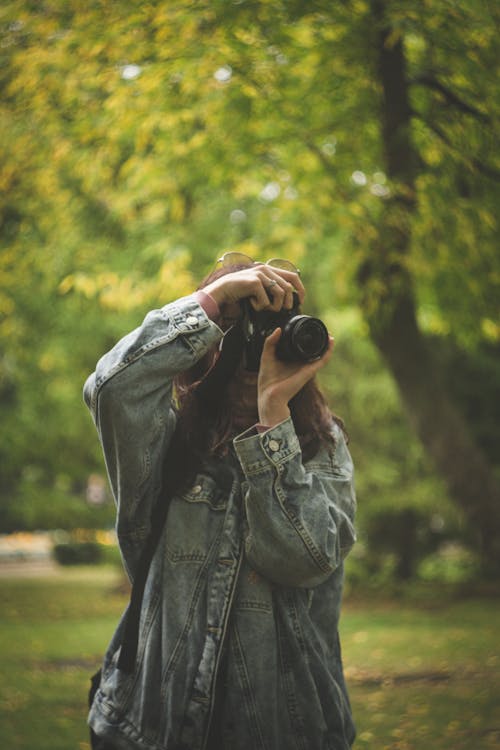 A Woman in Denim Jacket Taking Photo with a Camera