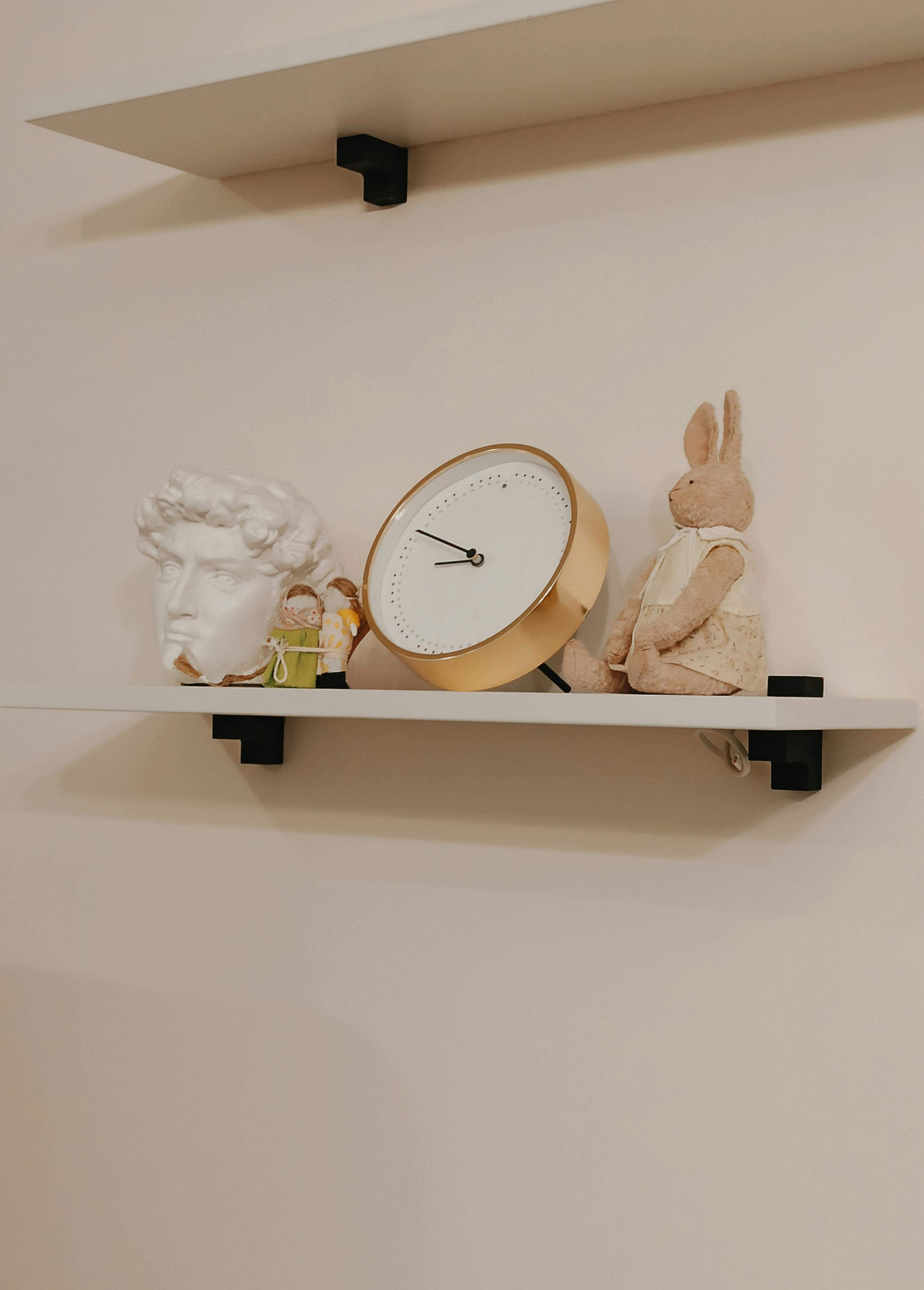 a white and gold analog clock on shelf