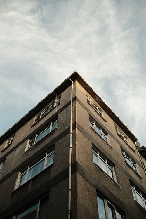 Free A low-angle shot of an urban building facade with windows against a blue sky. Stock Photo