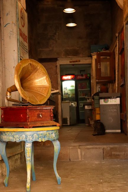 A vintage gramophone on an ornate table in a rustic indoor setting with warm lighting.