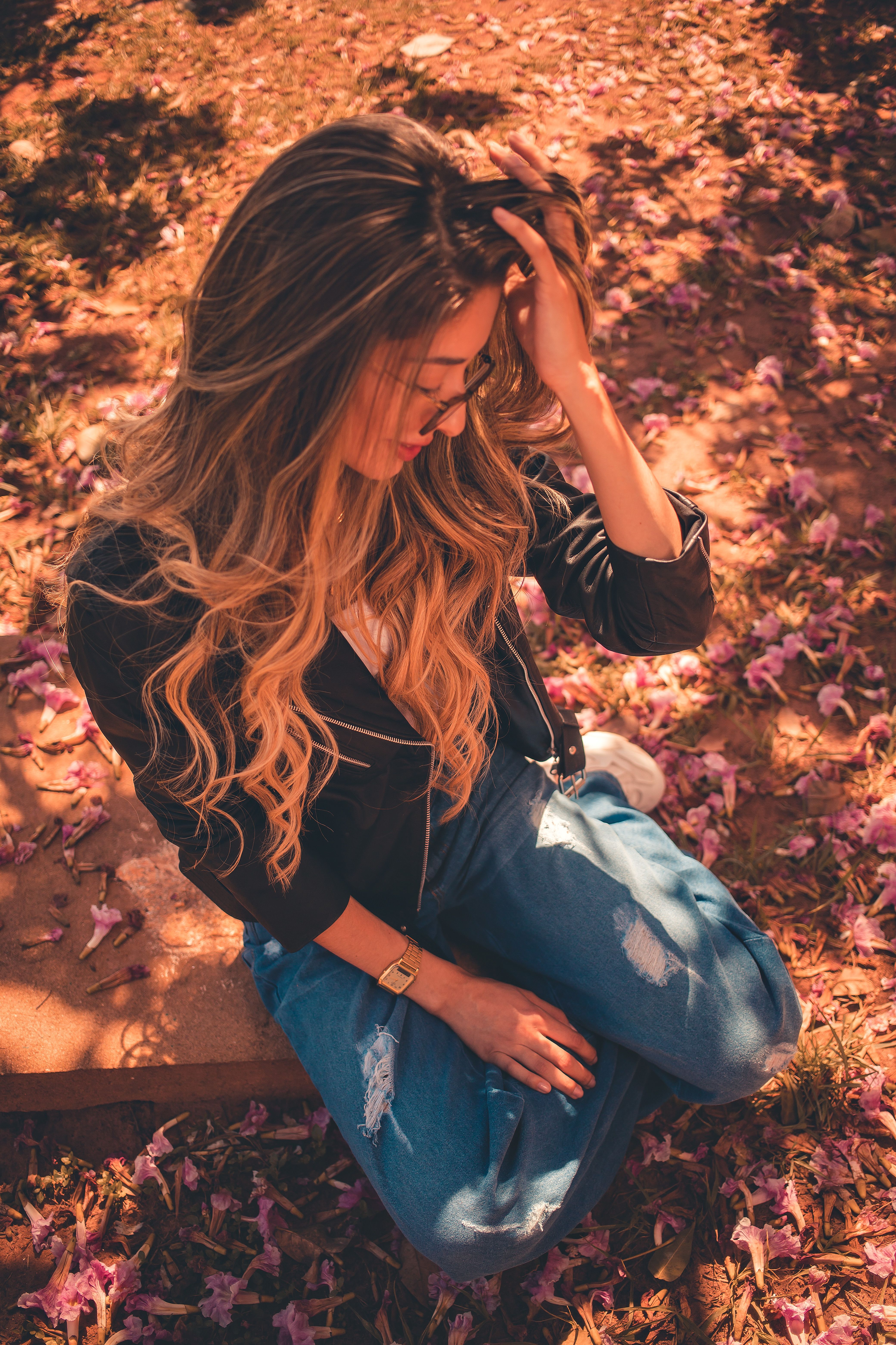A Woman in Black Jacket and Blue Denim Jeans Sitting on Brown Rock ...