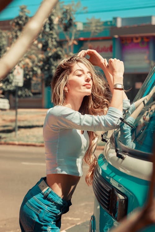 A Woman in White Long Sleeve Shirt and Blue Denim Pants Standing on Road