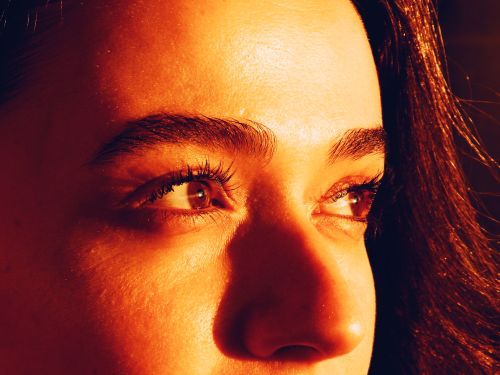 Free A detailed close-up portrait of a woman's eyes with warm light creating a dramatic effect. Stock Photo