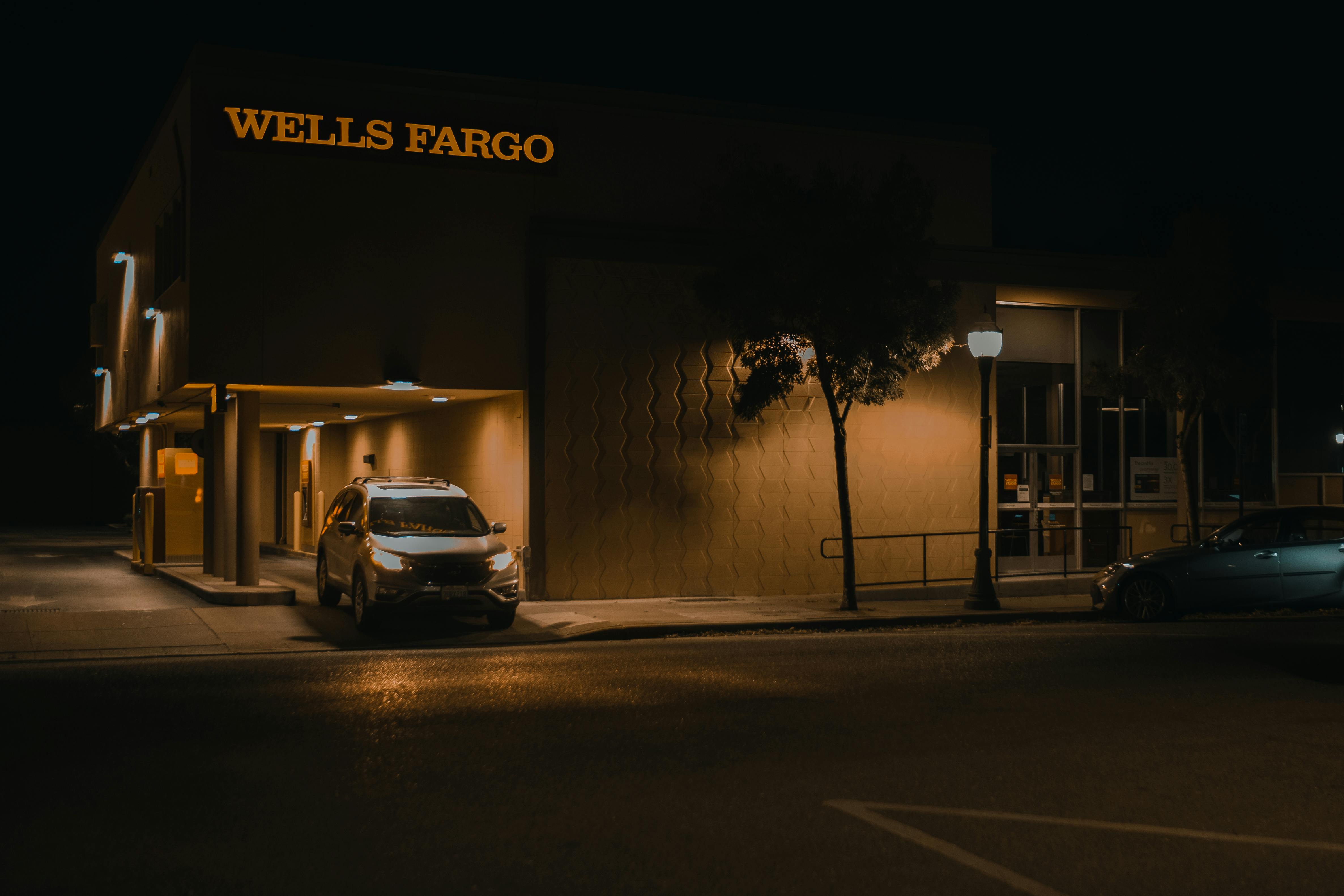 Illuminated Wells Fargo bank branch at night showcasing modern architecture and signage.