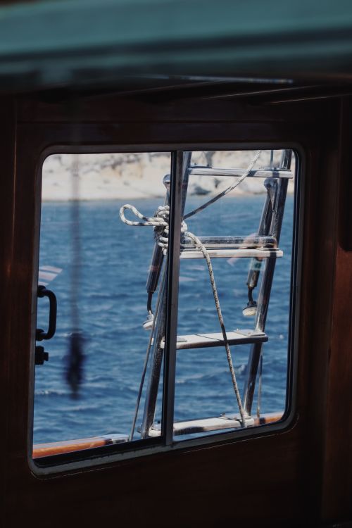 Free A nautical scene captured through a boat's window showing a ladder and sea. Stock Photo
