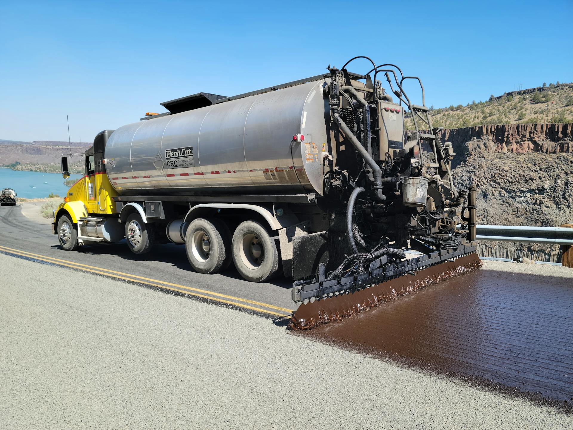 Chip seal truck applying asphalt on a highway near lake in Madras, Oregon.