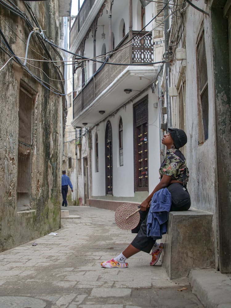 A Person Wearing Hat Sitting On Concrete Bench