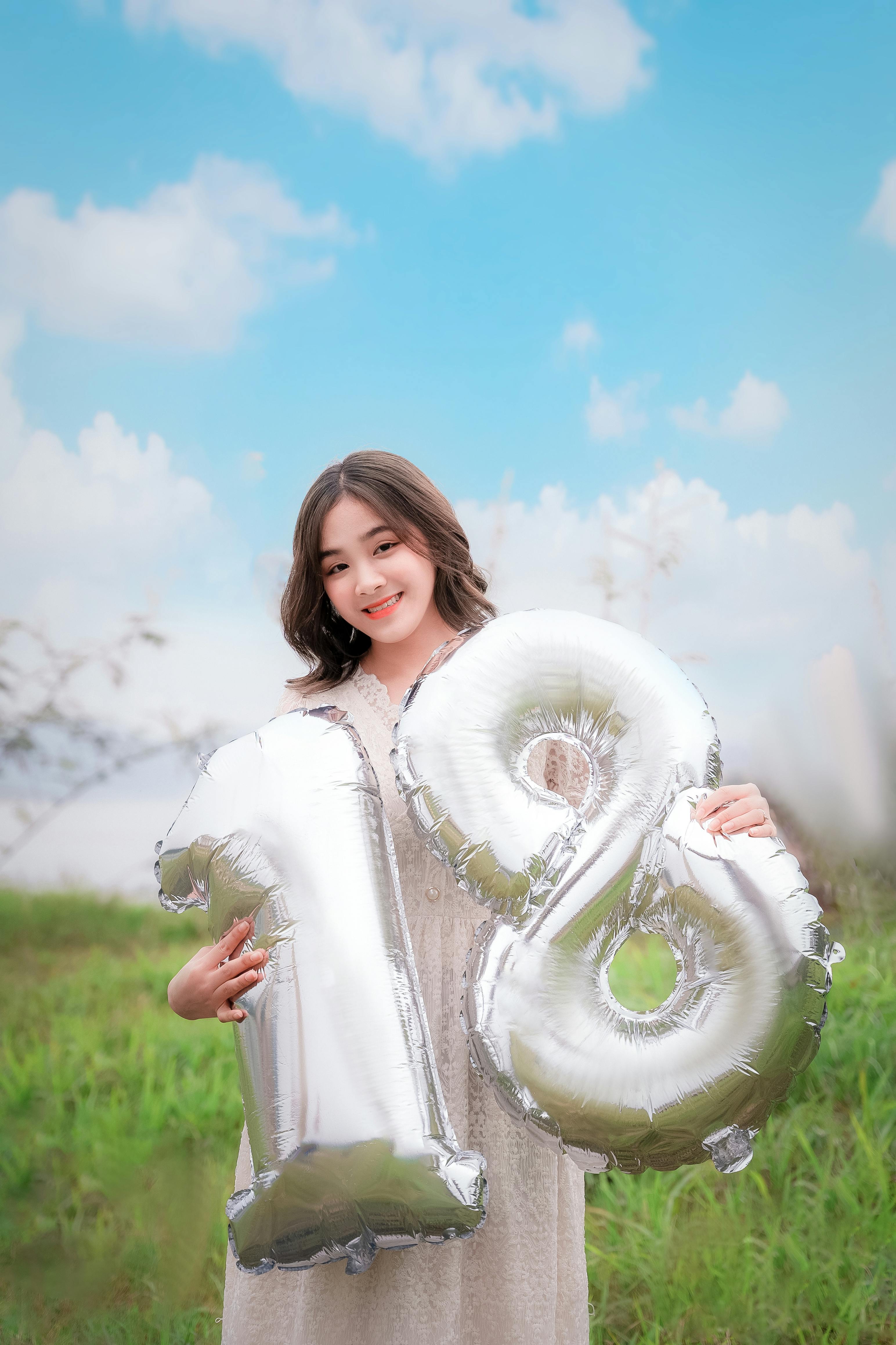Woman Holding Inflatables on Grass Field · Free Stock Photo