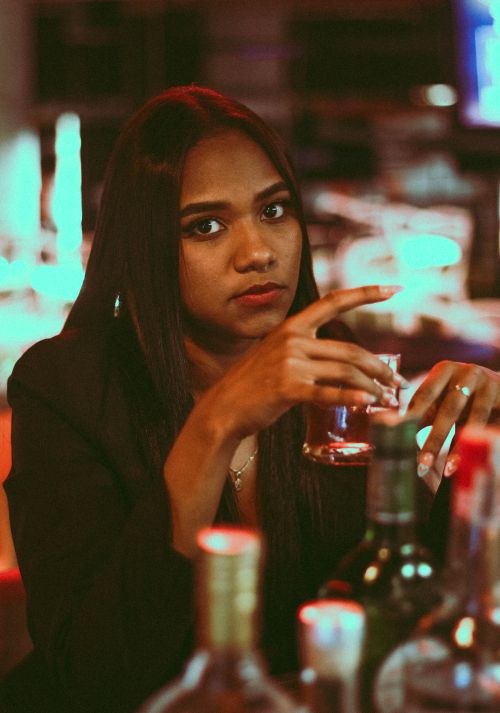Free A modern portrait of a stylish woman enjoying a drink at an indoor bar setting. Stock Photo