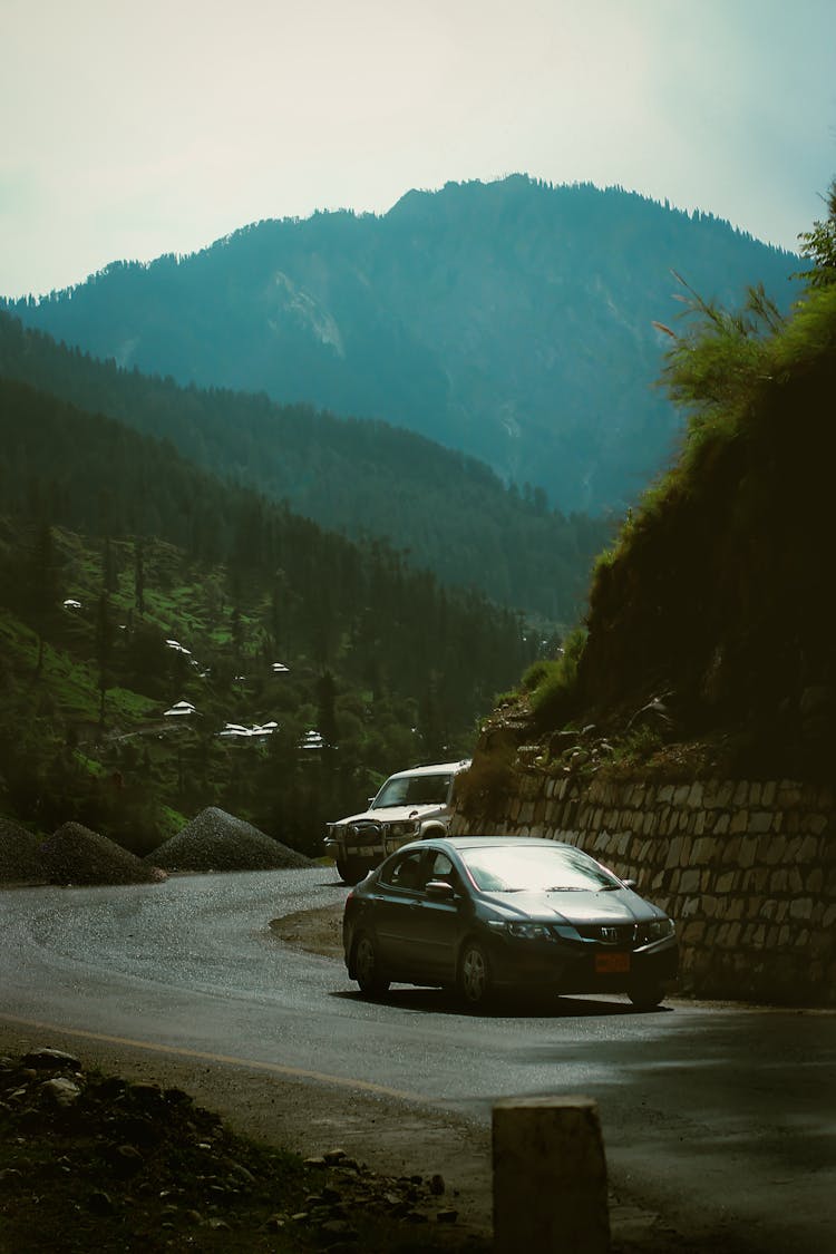 Cars Driving On Winding Road In Mountain Landscape