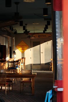 Charming outdoor dining area with wooden tables and chairs, warm lighting, and signs.
