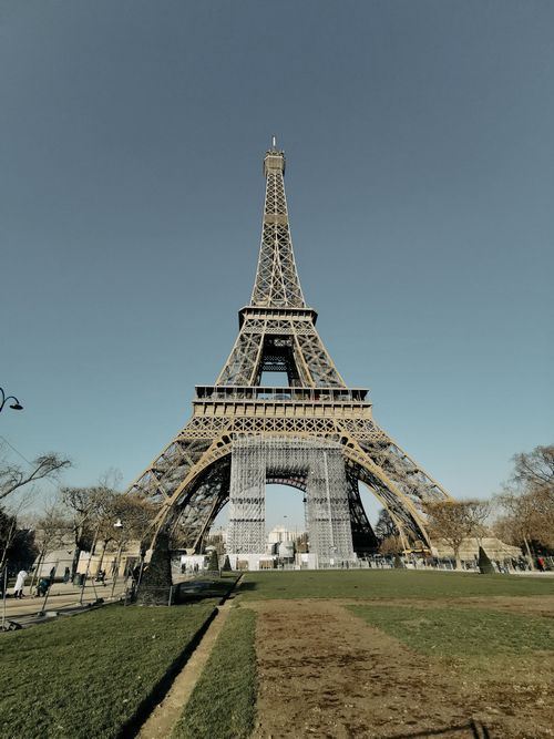 Free Low-angle view of the Eiffel Tower in Paris, a famous landmark under a blue sky. Stock Photo