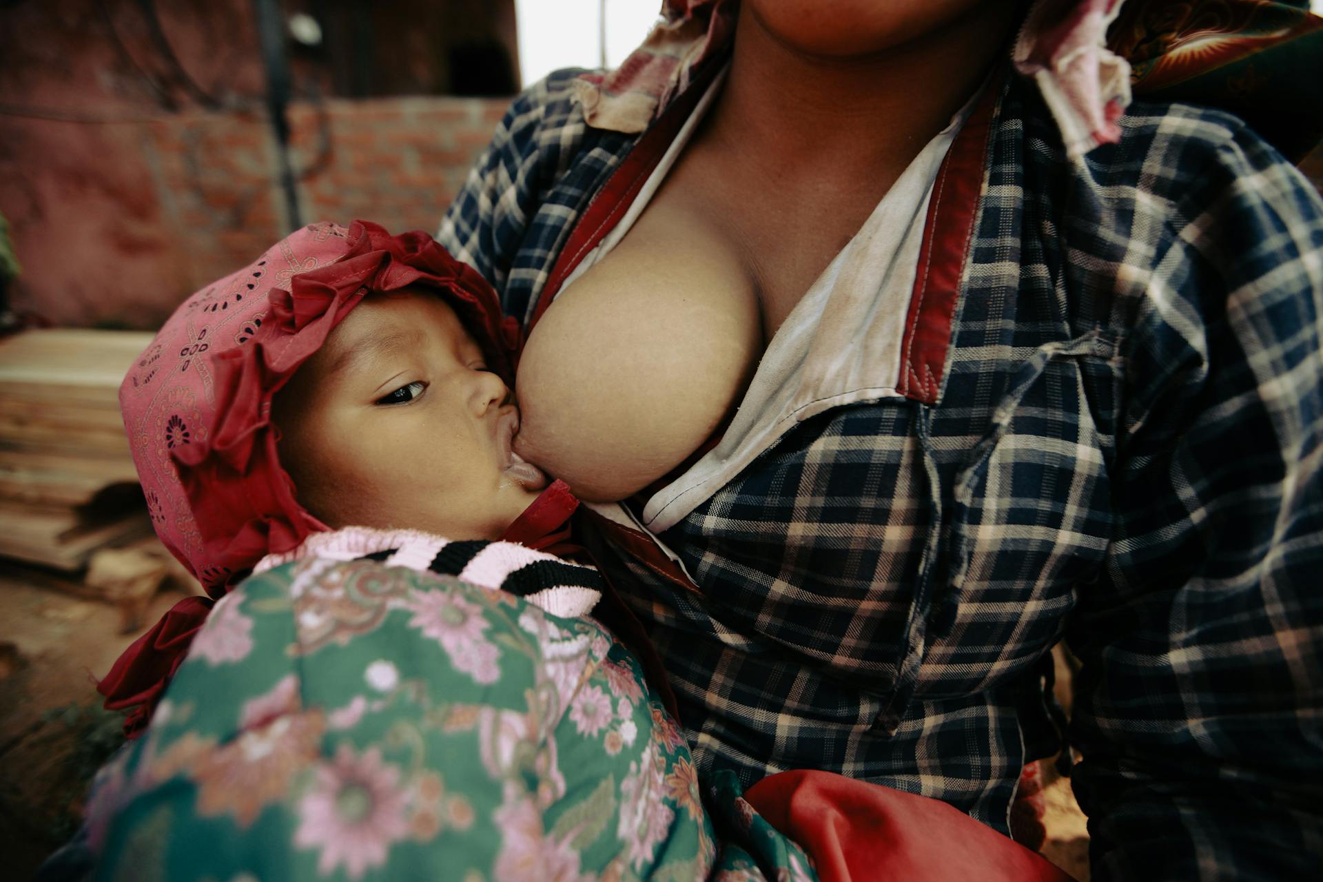 A mother tenderly breastfeeds her baby, showcasing a moment of care and bonding.