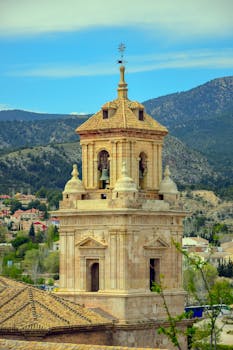 Majestic view of a historic bell tower against a mountainous backdrop in Caravaca de la Cruz, Spain.