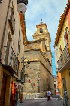 Explore the historic charm of Caravaca de la Cruz with this stunning view of the church on a quaint, narrow street.