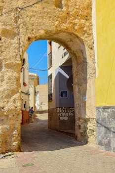 A stunning view of a historic stone archway in the sunny streets of Cehegín, Spain.