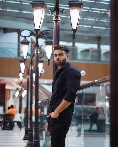 Man in Black Long Sleeves Standing near Lamp Posts