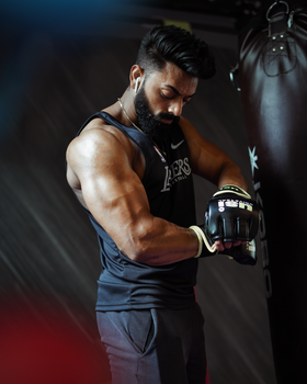 Muscular man getting ready for boxing session with sports gloves in the gym.