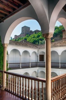 Beautiful view of the Alhambra from a traditional courtyard with arched columns.