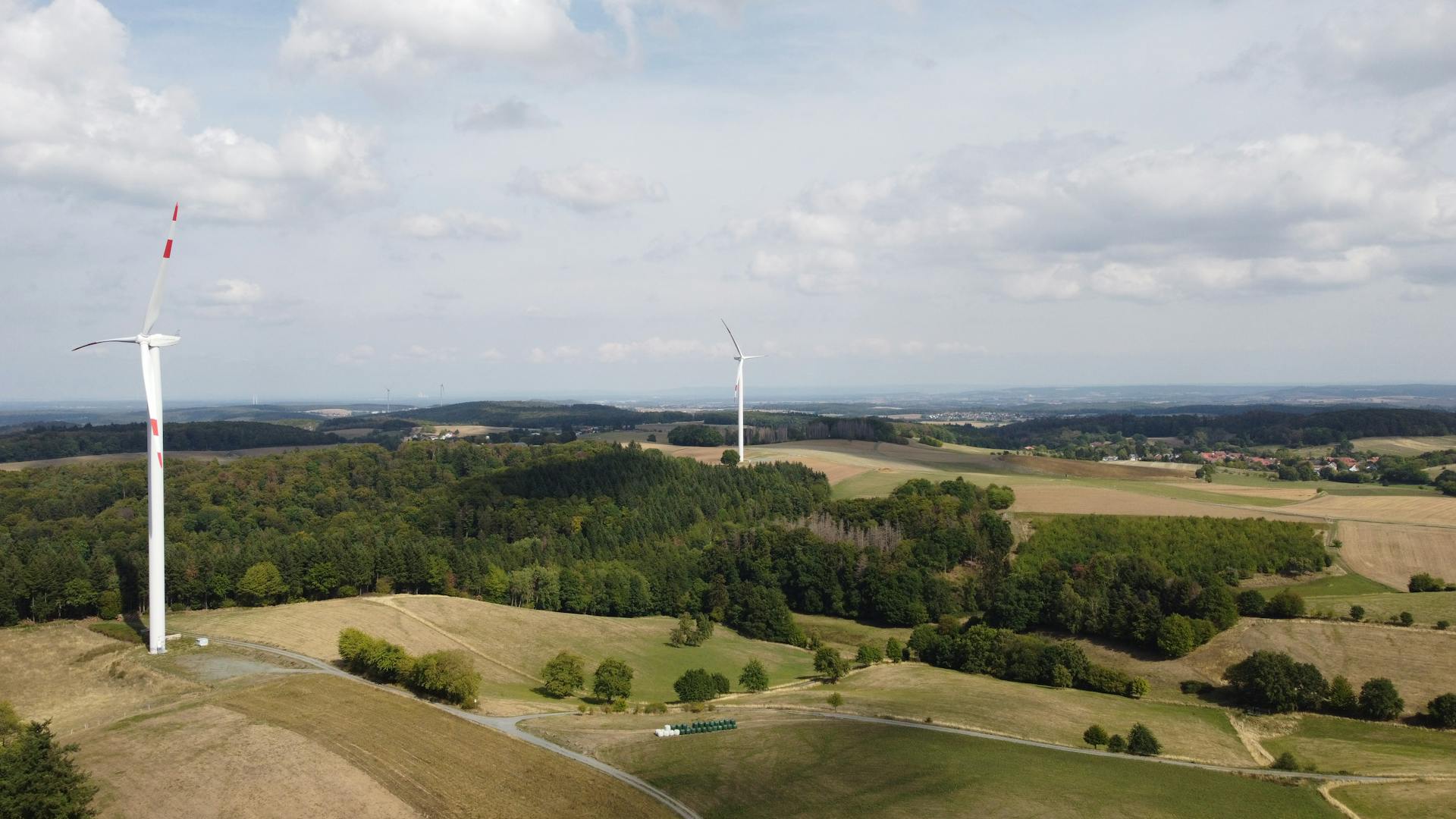 White Wind Turbine on Green Grass Field Under White Clouds