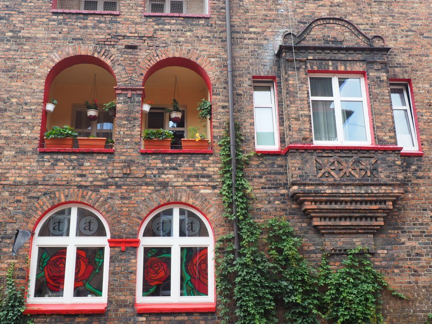 Charming brick building facade in Katowice, Poland featuring arched windows with decorative climbing plants.