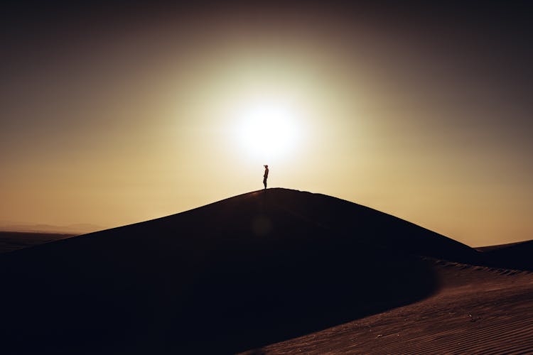 Silhouette Of Person On Hill In Desert On Sunset