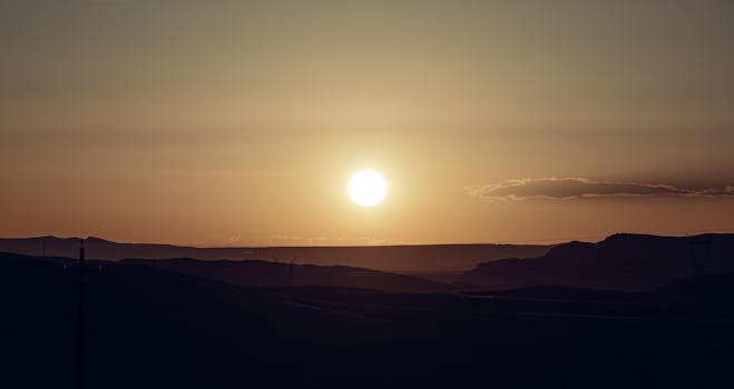 Serene sunset with clear sky and silhouetted mountain range, capturing the golden hour's beauty.