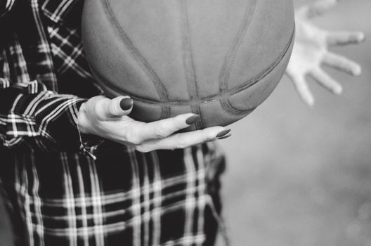 Monochrome image of hands holding a basketball, emphasizing texture and motion.