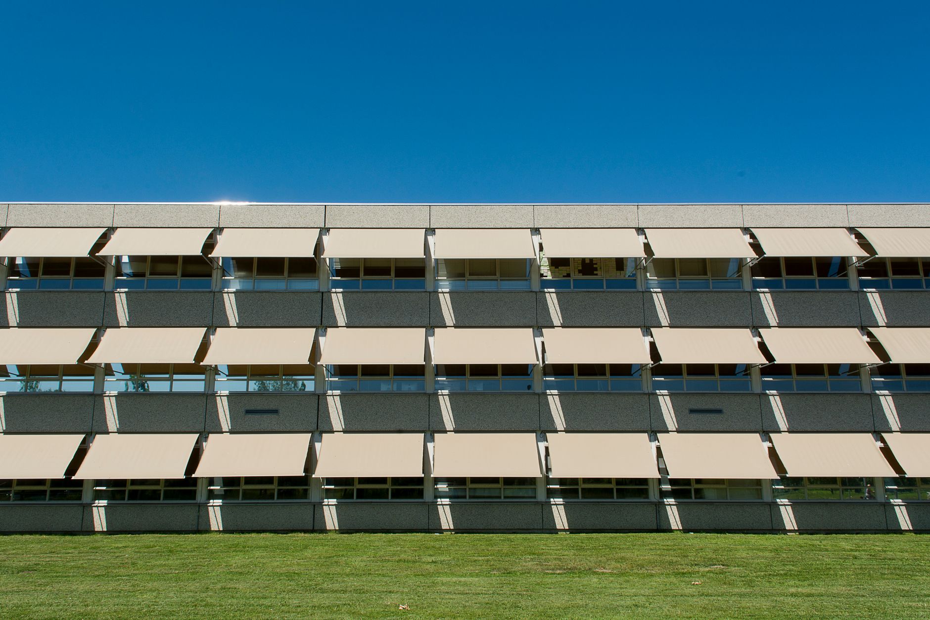 Geometric facade of a modern building with concrete exterior and glass windows.