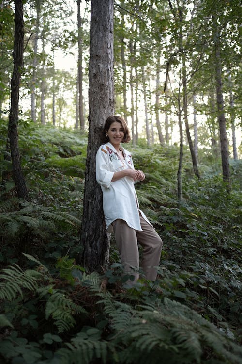 Woman in White Long Sleeves Leaning on a Tree in the Forest