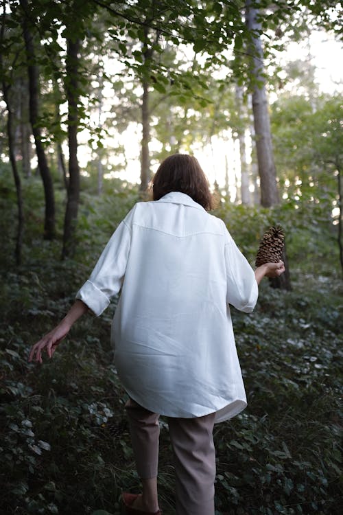 Woman in White Long Sleeves Walking in the Forest
