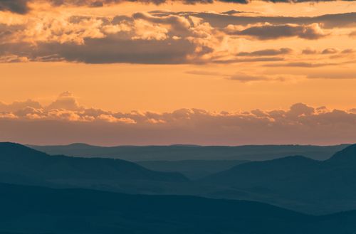 Free A calming view of mountain silhouettes against a vibrant sunset sky. Stock Photo