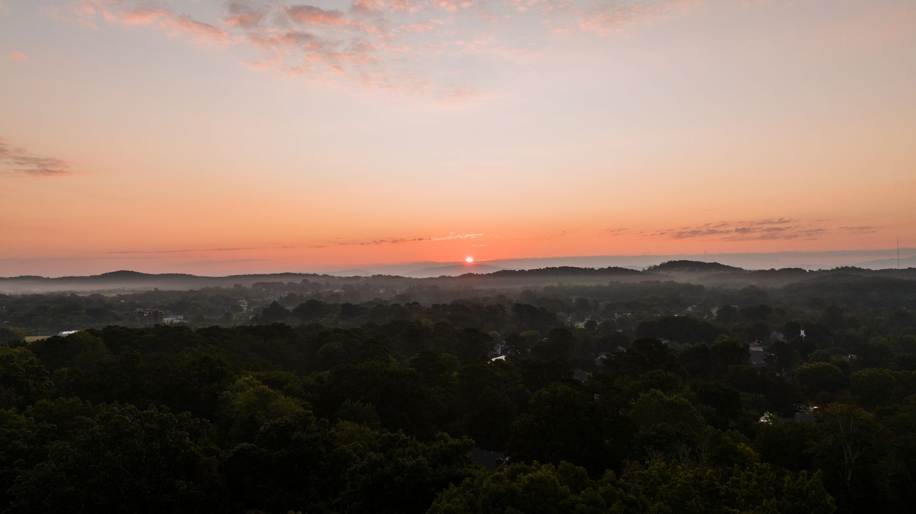 A stunning aerial view of the sunset over lush trees in Cleveland, TN.