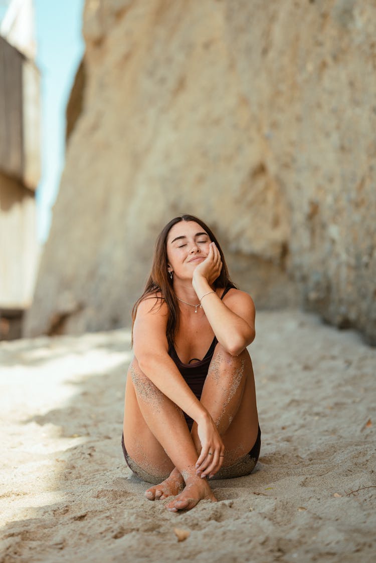 A Woman In Black Tank Top Sitting On The Beach