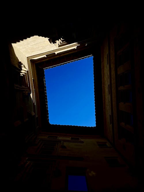 Upward View of a Dark Attic Ceiling and Blue Sky behind a Window