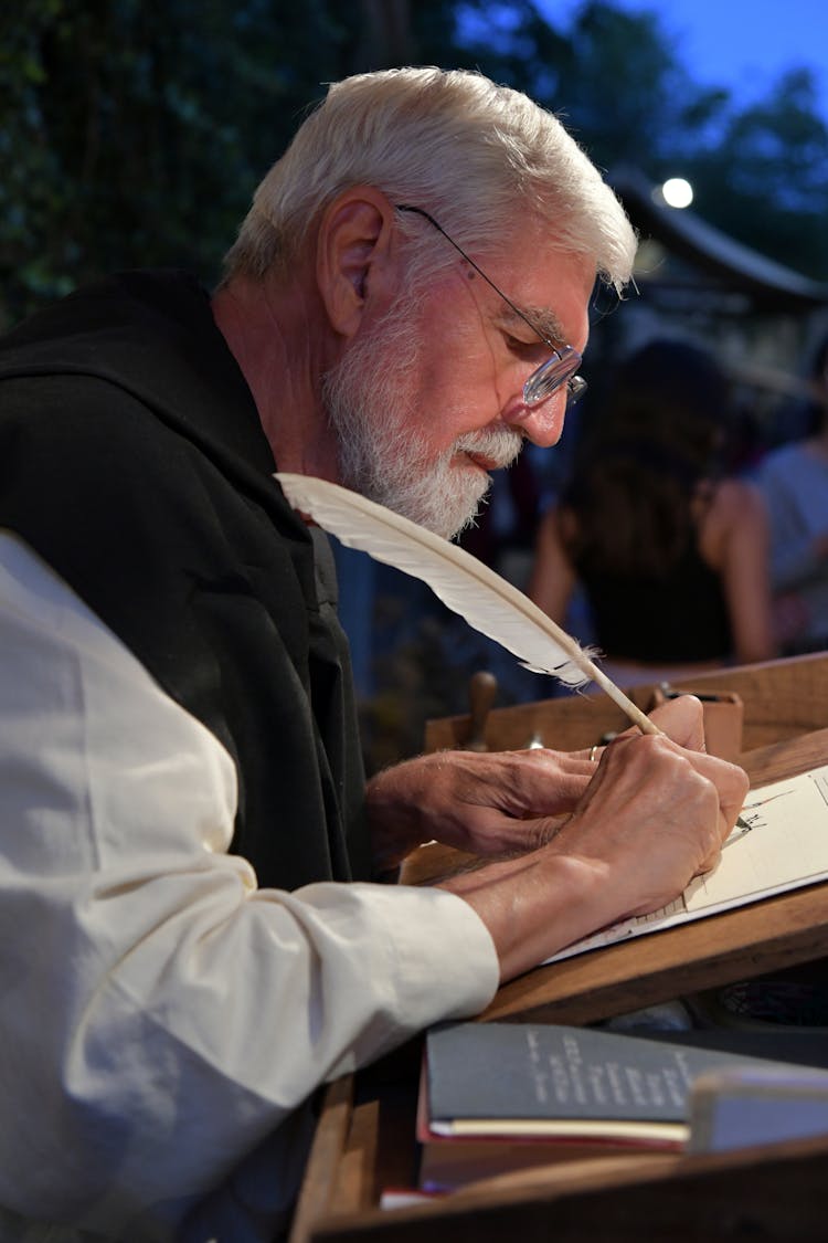 Man In White Dress Shirt Writing On White Paper With A Quill Pen