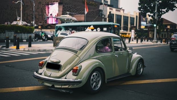 Classic Volkswagen Beetle driving in urban setting, showcasing retro charm.