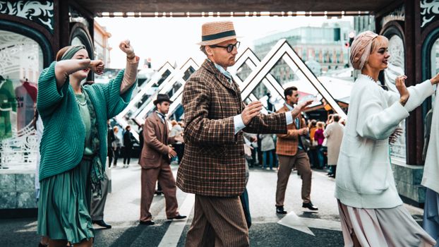 A vibrant street festival captures dancers in vintage attire enjoying a lively outdoor celebration.