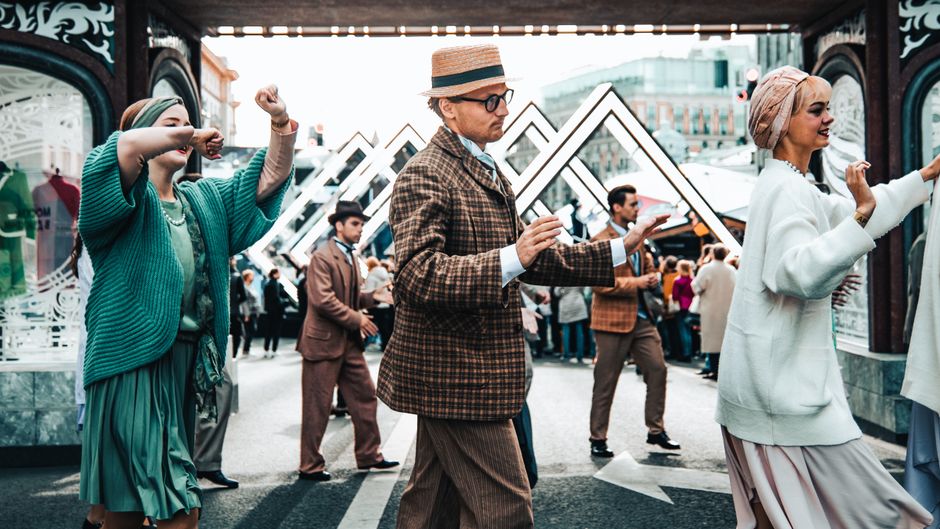 A vibrant street festival captures dancers in vintage attire enjoying a lively outdoor celebration.