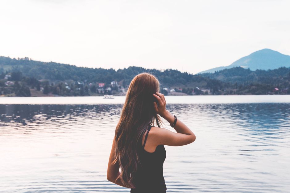 A woman gazing across the tranquil waters of Colibița Reservoir, Romania.