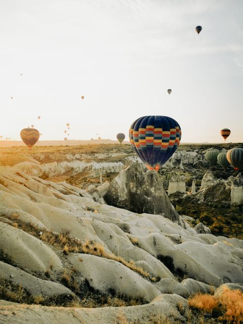 Free Stunning view of hot air balloons soaring over the rocky landscape of Cappadocia at sunrise. Stock Photo