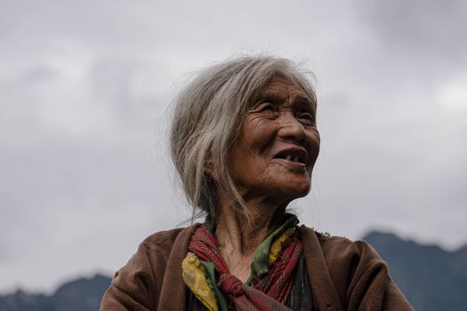Portrait of a senior woman smiling outdoors with a cloudy sky background. Embracing age gracefully.