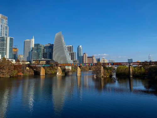 Free A stunning view of Austin's skyline with a bridge over the Colorado River under a clear blue sky. Stock Photo