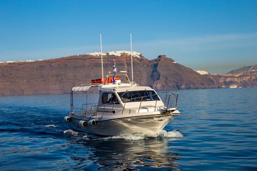 A sleek white yacht sailing against the beautiful backdrop of Santorini's dramatic cliffs under a clear blue sky.