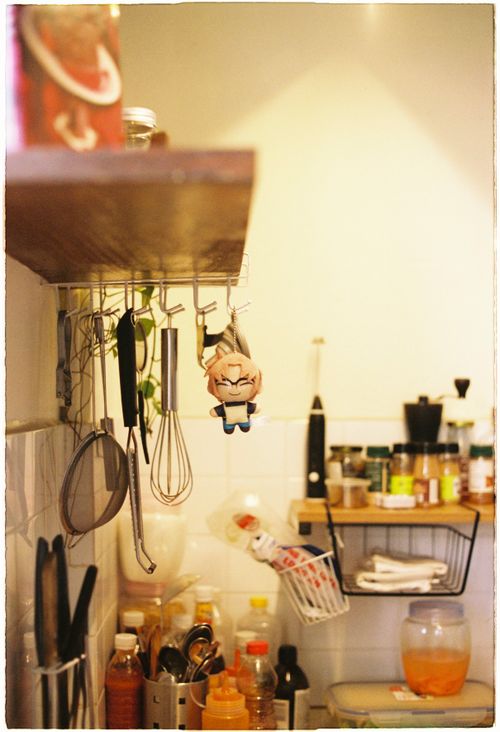 Free A warm kitchen scene with hanging utensils, spices, and a plush toy for a homely feel. Stock Photo